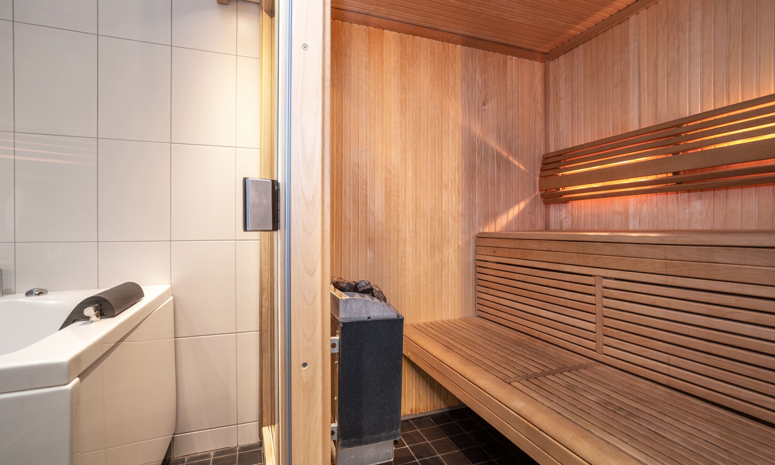 Una sauna con bancos de madera y un área de ducha independiente.