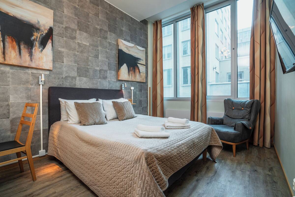 A hotel room with a large bed, a chair, and artwork on the walls.