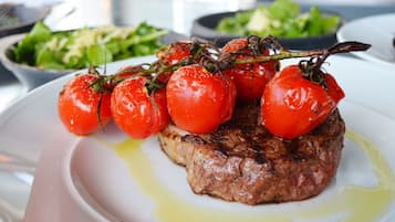 Un plato con un filete cubierto de tomates cherry y aceite de oliva.