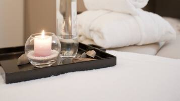 Experience a serene retreat with a lit candle, a clear glass bottle, and a potted plant, creating a calm and inviting atmosphere.