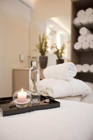 A neatly arranged bathroom with a white towel, a glass bottle, and a lit candle on a tray. - Hotel Gräfrather Hof (Solingen)