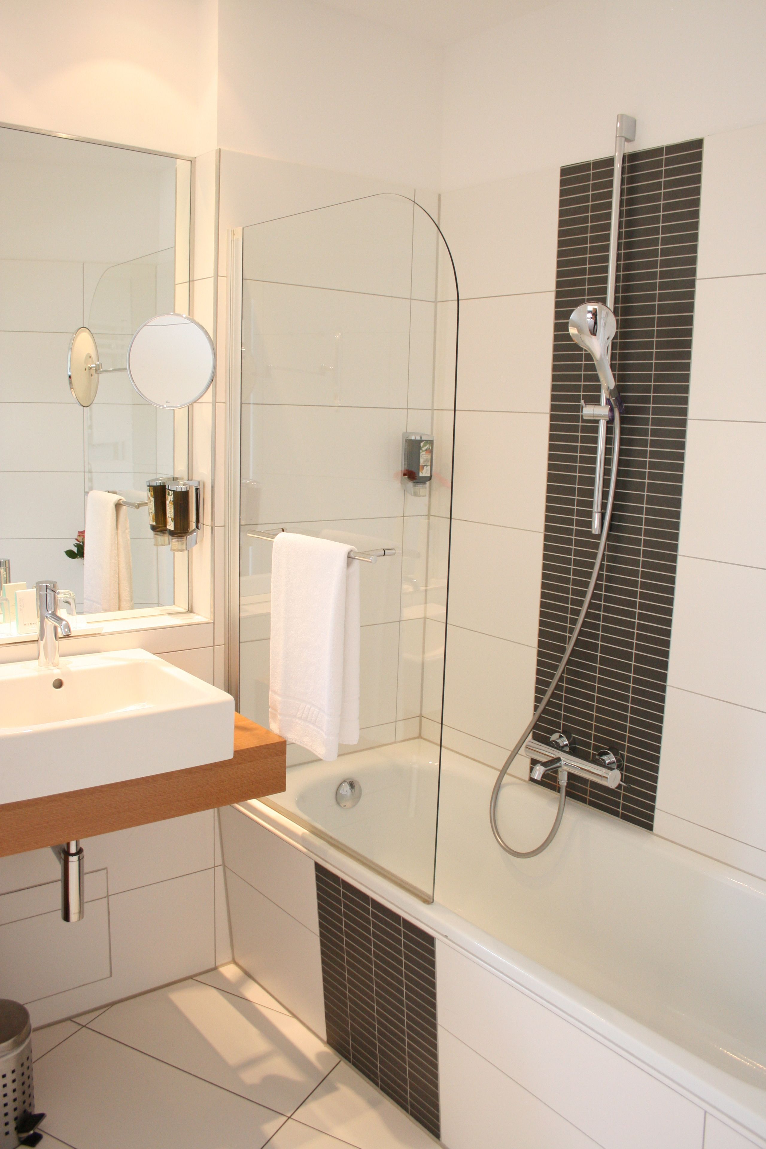 A modern bathroom with a glass-enclosed shower, a white sink, and a large mirror.