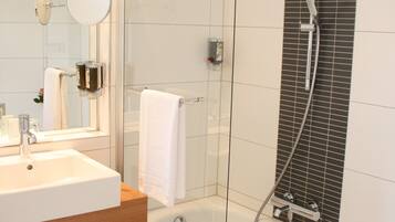 A modern bathroom with a glass-enclosed shower, a white sink, and a large mirror.