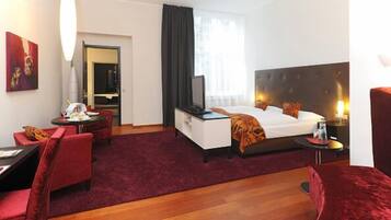 Ein Hotelzimmer mit Bett, Schreibtisch, Stuhl, Fernseher und einem fenster mit Vorhängen.