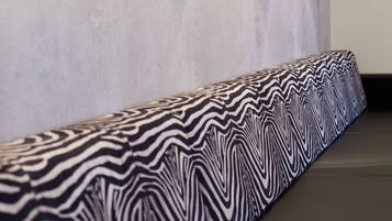 A bathroom with a patterned bench, wall-mounted lights, and a vent.