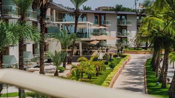 A modern hotel with multiple balconies, outdoor seating, and lush landscaping.