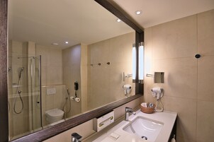 Un baño moderno con ducha envuelta en vidrio, un espejo grande y un lavabo con toallero.