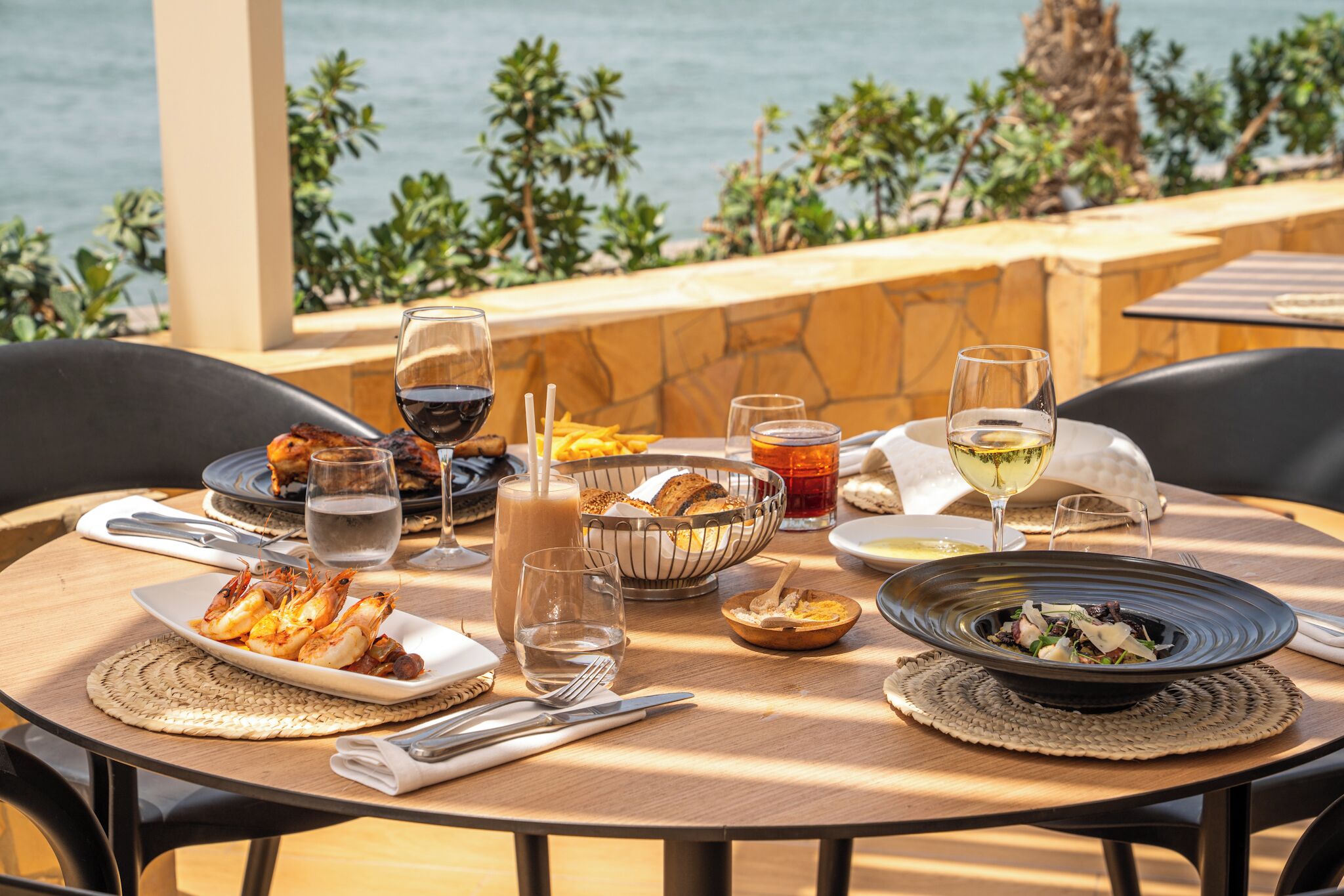 Une table dressée avec des fruits de mer, du pain et des verres à vin, offrant une vue panoramique.