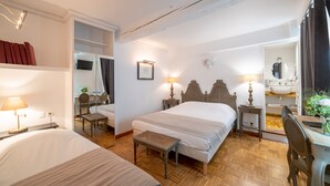 Une chambre d’hôtel avec un grand lit, des tables de chevet, un bureau, une chaise, un miroir et une salle de bain équipée d’un lavabo et d’un miroir.