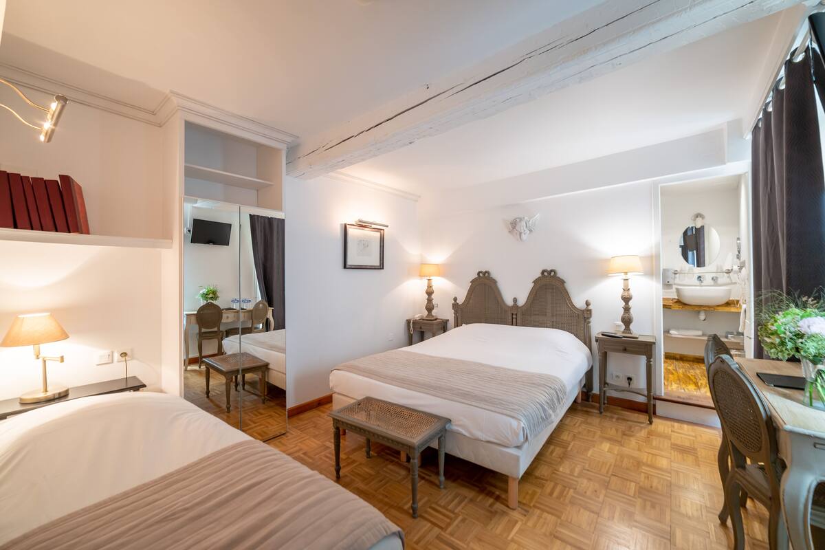 Een hotelkamer met een groot bed, nachtkastjes, een bureau, een stoel, een spiegel en een badkamer met een wastafel en spiegel.