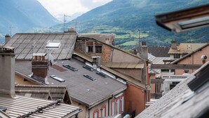 Une vue d’un paysage montagneux, avec des bâtiments au premier plan.