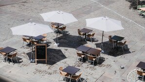 Un café en plein air avec des tables et des chaises, dont certaines sont dotées de parasols, et un menu écrit à la craie sur un tableau noir.