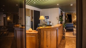 Un intérieur moderne avec un comptoir d’accueil en bois, une lampe, un canapé et une plante en pot.