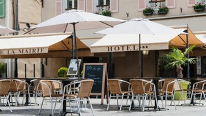 Terrassa de cafè a l'aire lliure amb ombrel·les, cadires de vímet i un quadre per al menú.
