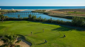 A golf course with a view of the ocean and a bridge.
