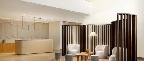 Un vestíbulo moderno con mostrador de recepción, zona de estar y un separador decorativo.