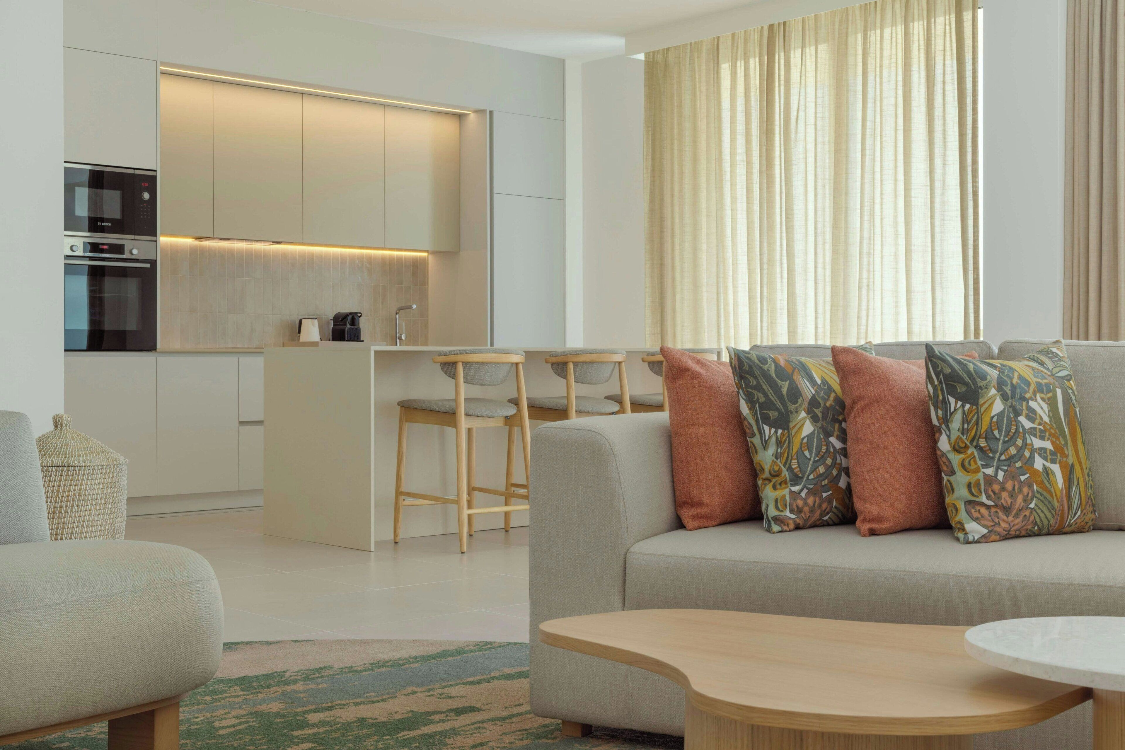 Una sala de estar moderna con un sofá, una mesa de centro y una cocina al fondo.