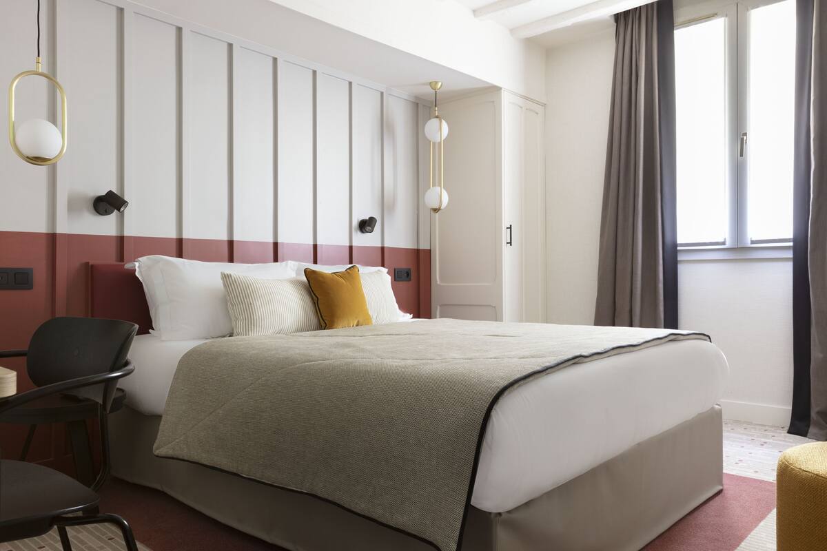 A modern hotel room with a large bed, a desk, and a chair.