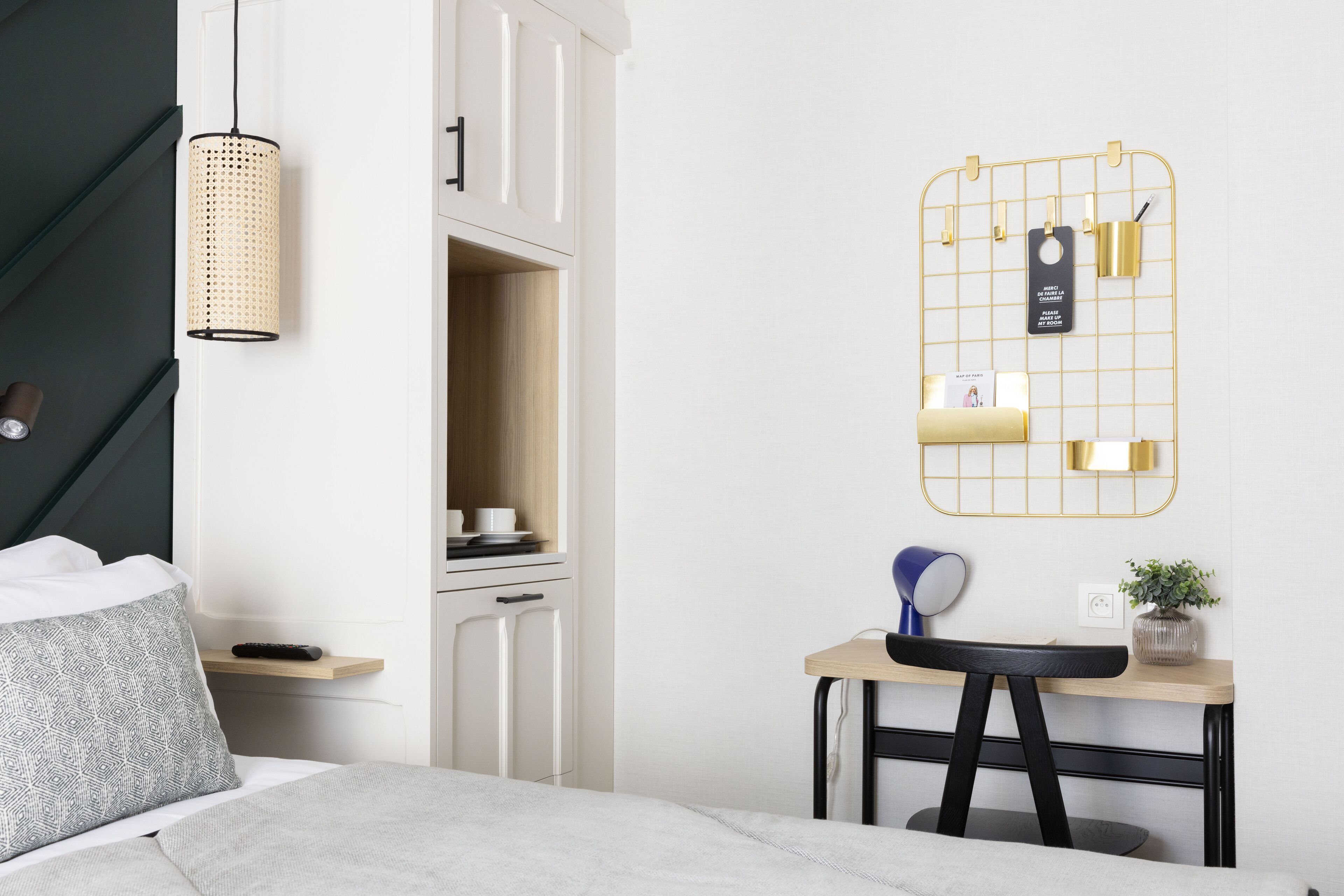 A modern bedroom with a bed, bedside table, desk, chair, and a wall-mounted organizer.