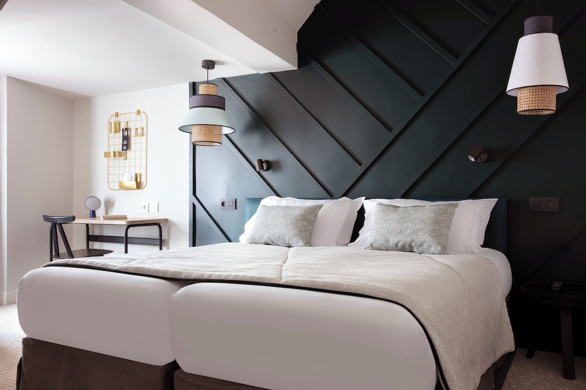 A modern bedroom with a large bed, a desk, and two pendant lights.