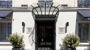 A hotel entrance with a glass canopy, two potted plants, and signs reading "Bastille Espagne". - Hotel Bastille Spéria (Paris)