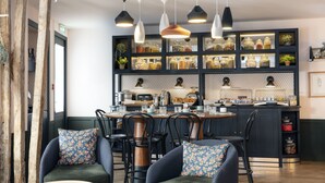 A modern kitchen with a central island, black cabinetry, and a variety of kitchen appliances. - Hotel Bastille Spéria (Paris)