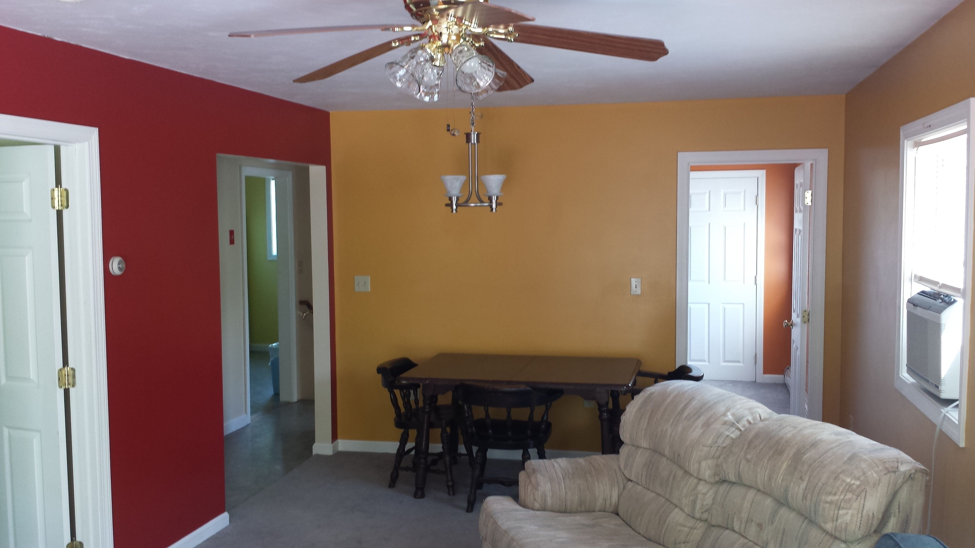 A dining area with a table and chairs, a ceiling fan, and a couch.