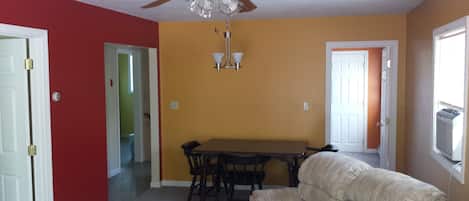A dining area with a table and chairs, a ceiling fan, and a couch.
