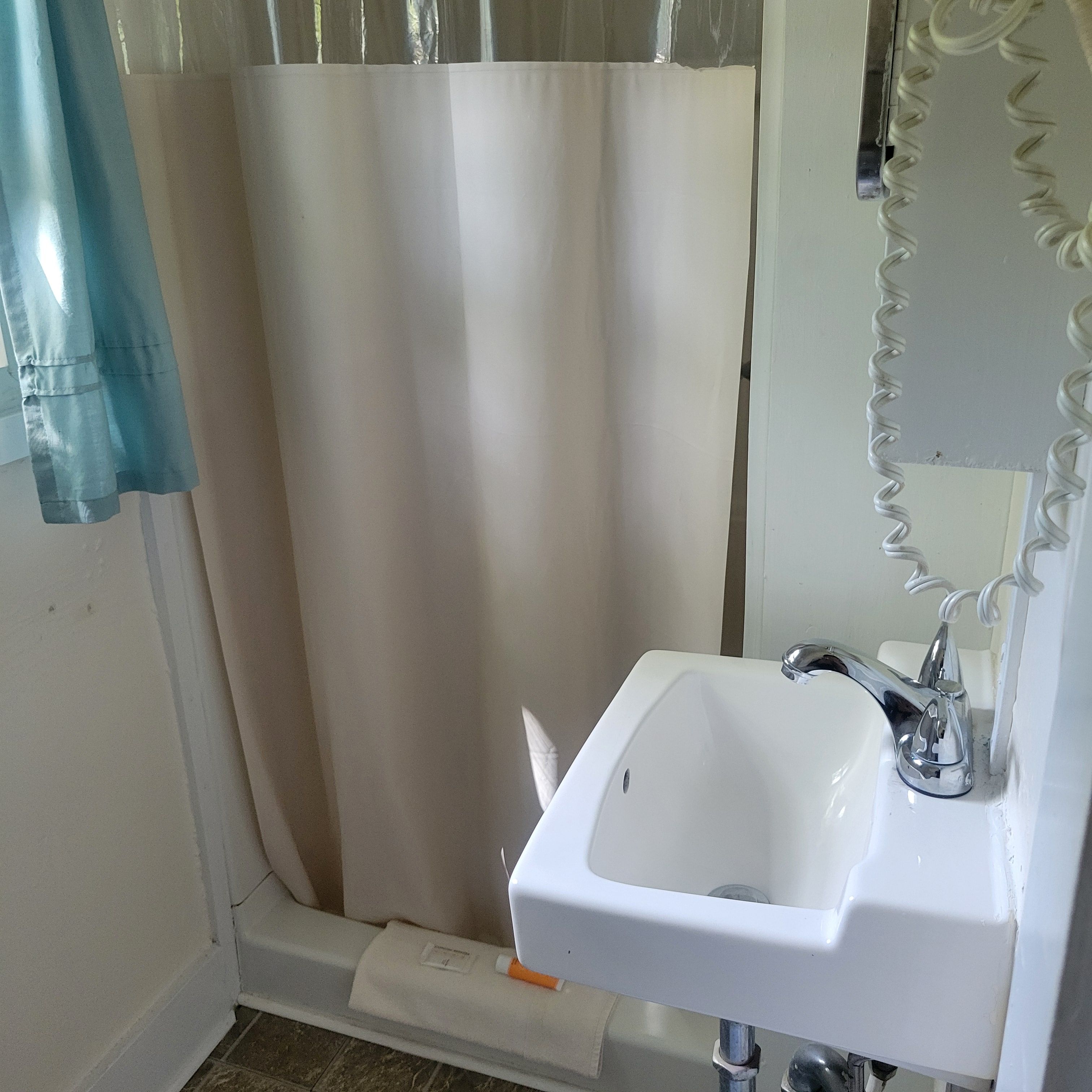 A bathroom with a white sink, a mirror, and a shower curtain.