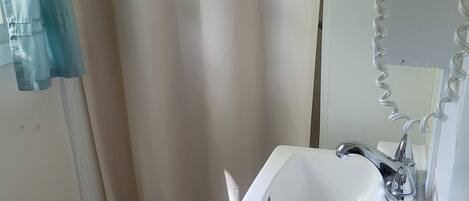 A bathroom with a white sink, a mirror, and a shower curtain.