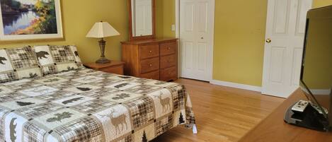 A bedroom with a bed, a dresser, a lamp, a mirror, and a door.