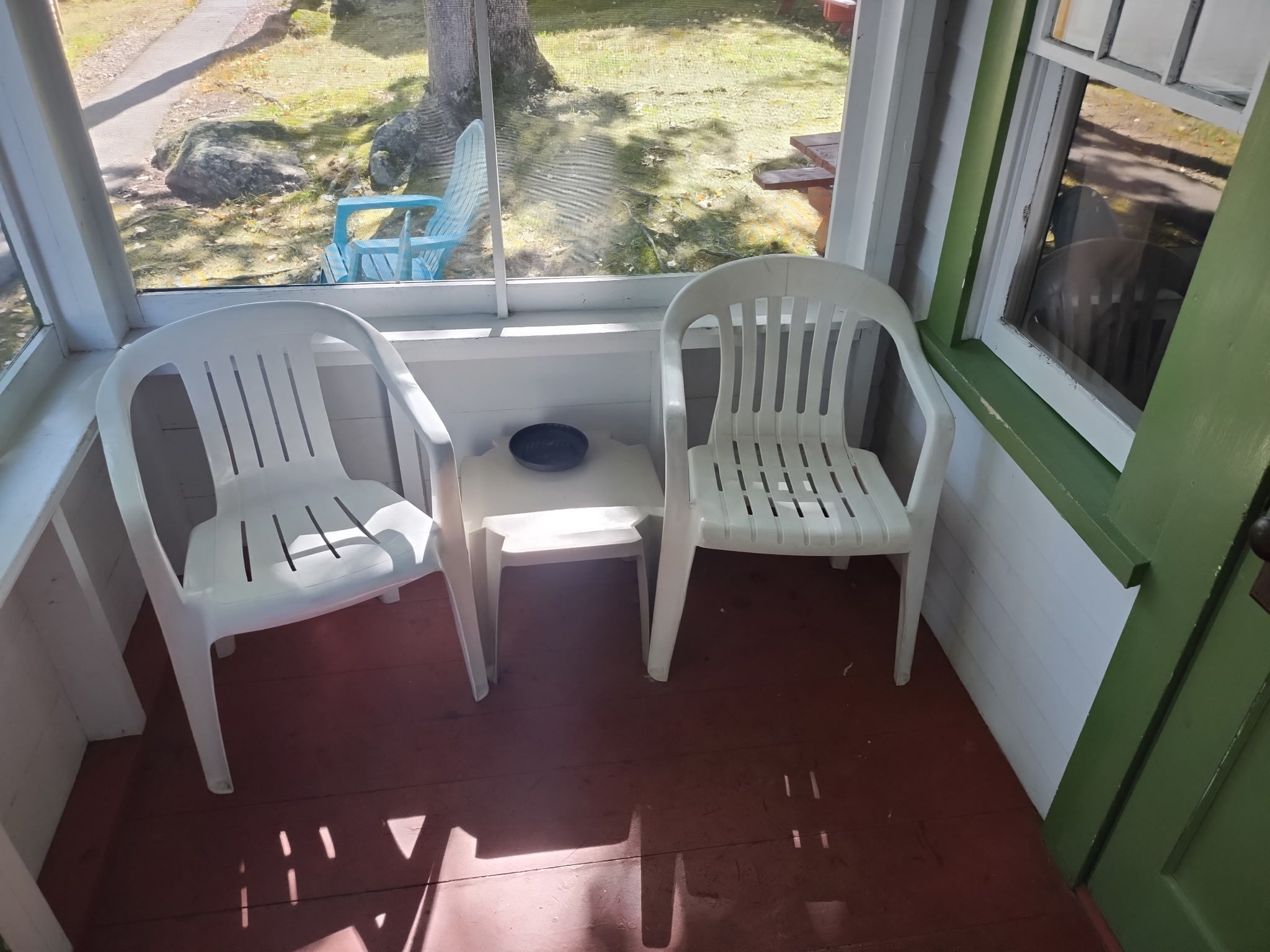 Een veranda met twee witte plastic stoelen en een kleine tafel.