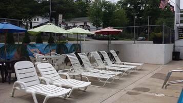 Outdoor lounge chairs and umbrellas, a mural, and a 'No Parking' sign.