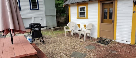 Un espace extérieur aménagé avec un barbecue, des chaises et une table.