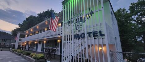 Een motel met een veranda, buiten zitplaatsen en een Amerikaanse vlag.