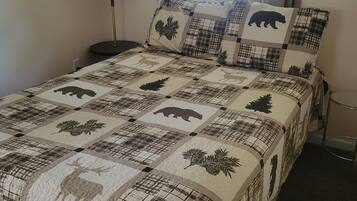 A bed with a quilt featuring animal prints and a lamp beside it.
