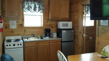 Une petite cuisine avec des meubles de rangement en bois, un four à micro-ondes, un réfrigérateur, une cuisinière et un évier.