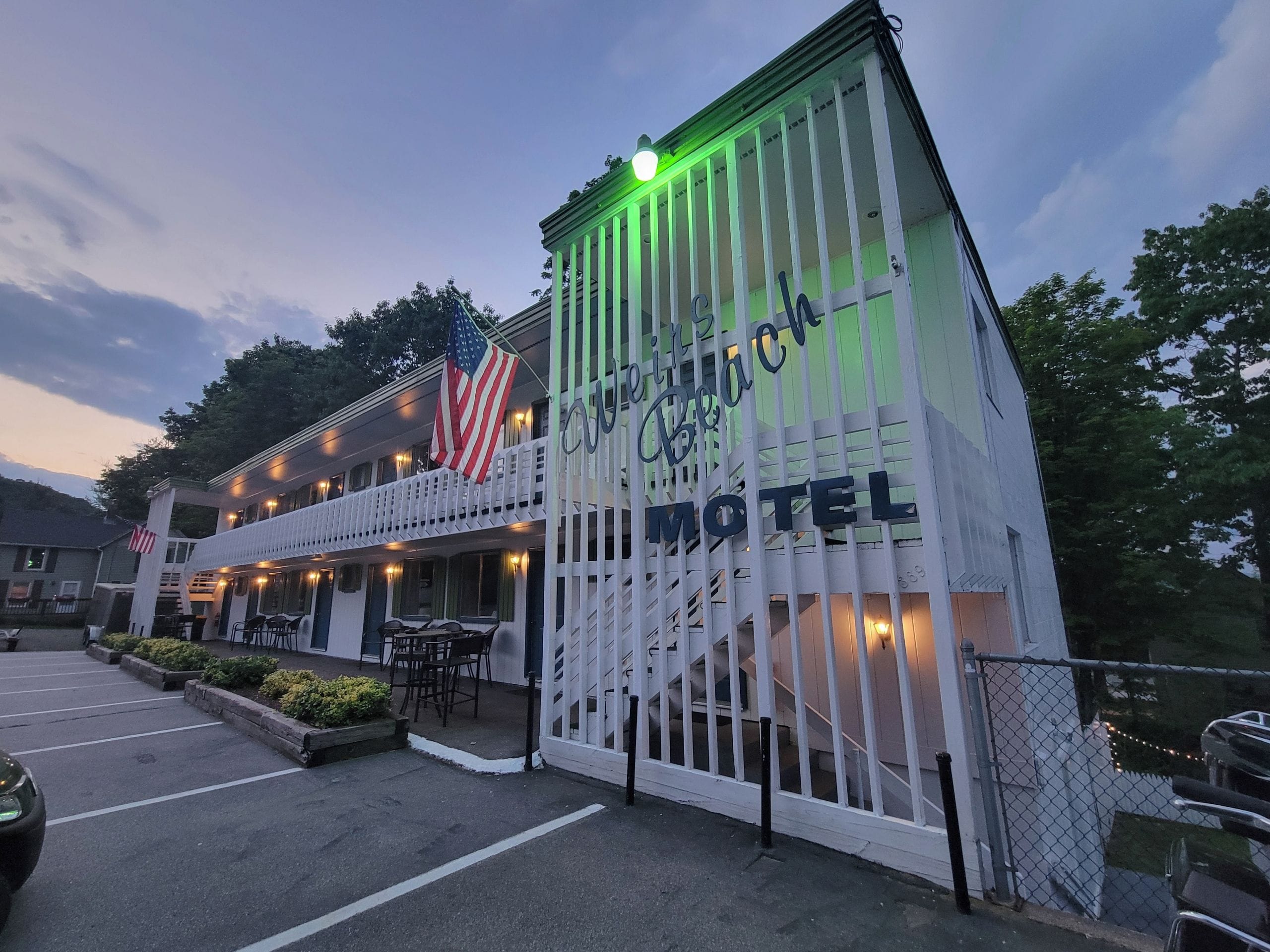 A motel with a porch, outdoor seating, and an American flag.