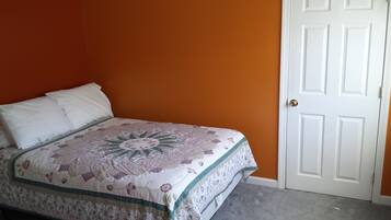 Une chambre à coucher avec un lit, une porte blanche et des murs orange.