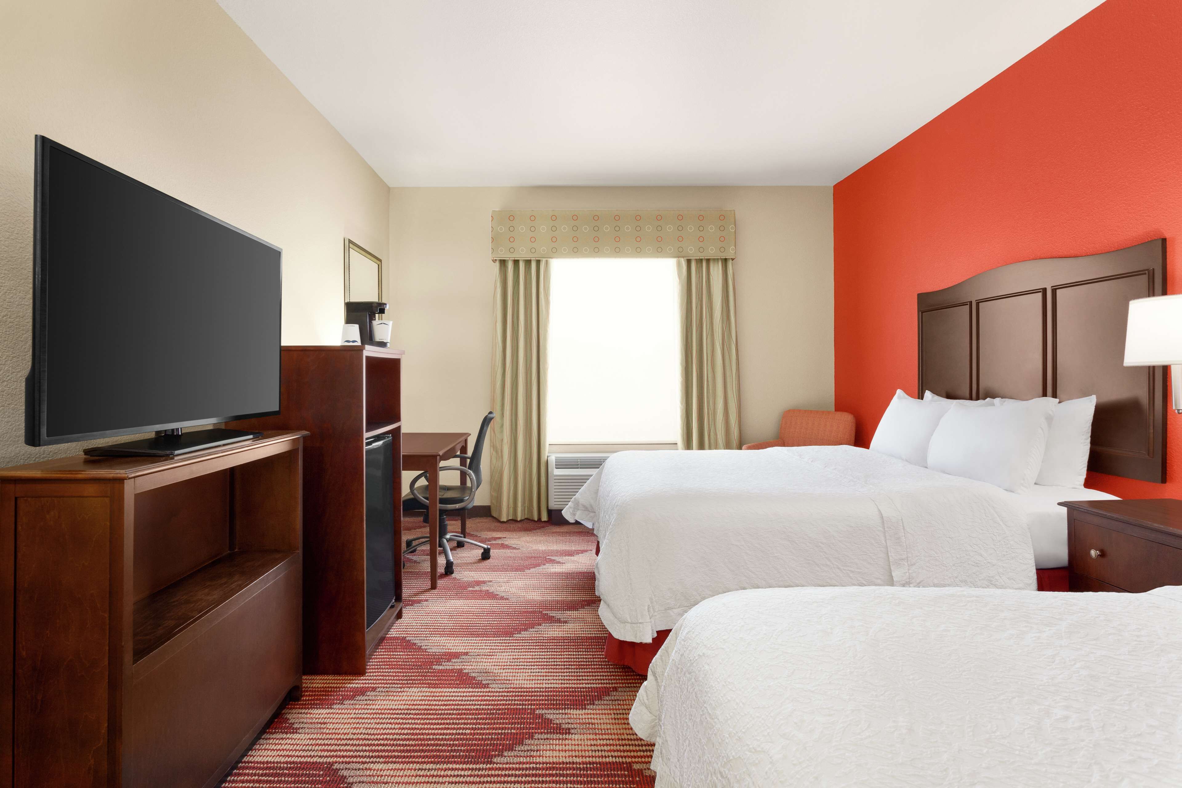 Une chambre d’hôtel avec deux lits, une télévision, un bureau et une chaise.