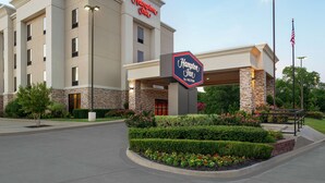 Hampton Inn by Hilton -hotellin rakennus, jossa on kiviverhous, suuri kyltti ja hoidetut puutarhat.
