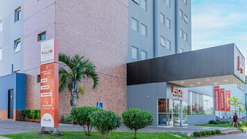 Um hotel moderno com uma placa chamativa, um gramado bem cuidado e uma entrada visível.