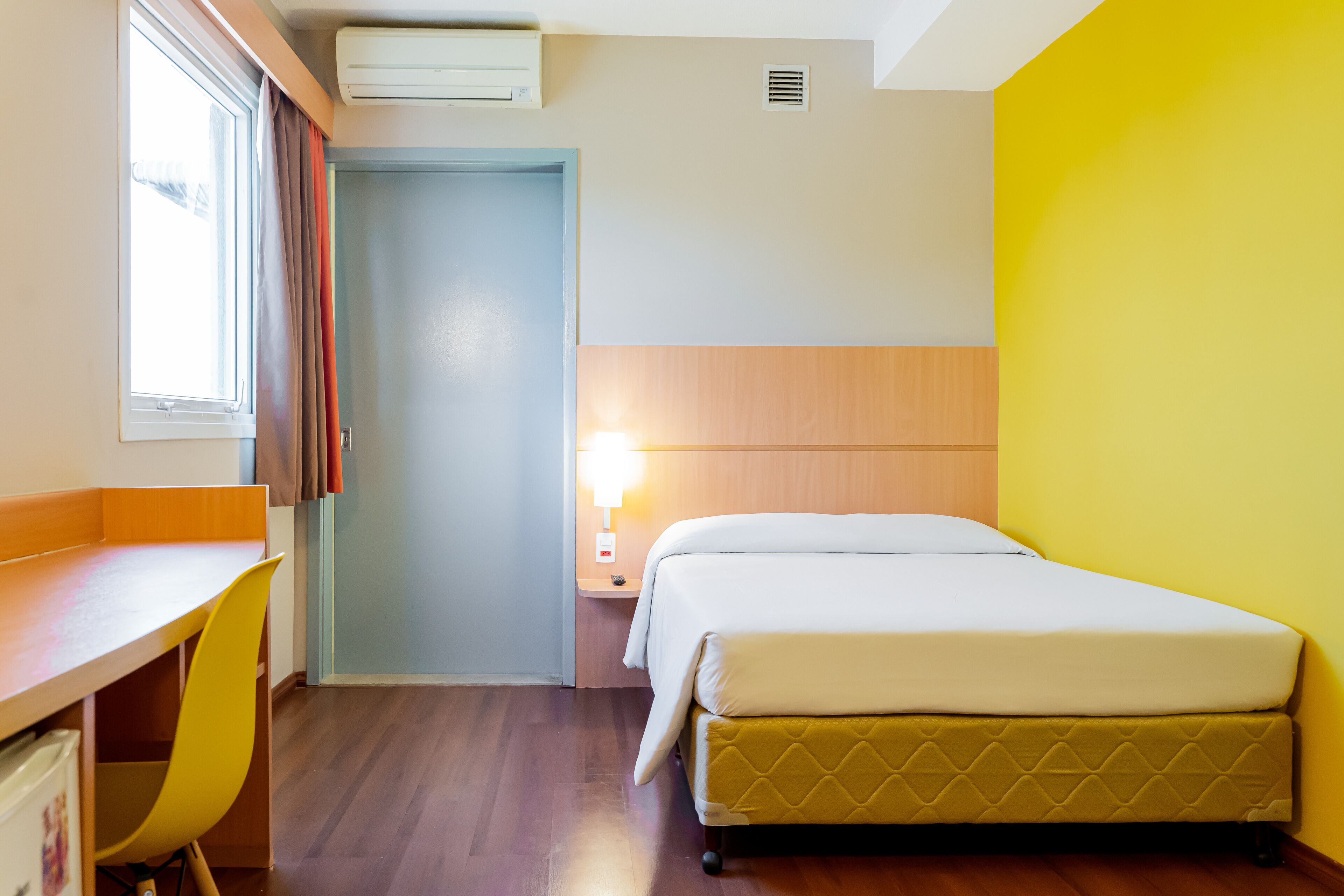 A hotel room with a bed, a desk, and a chair.