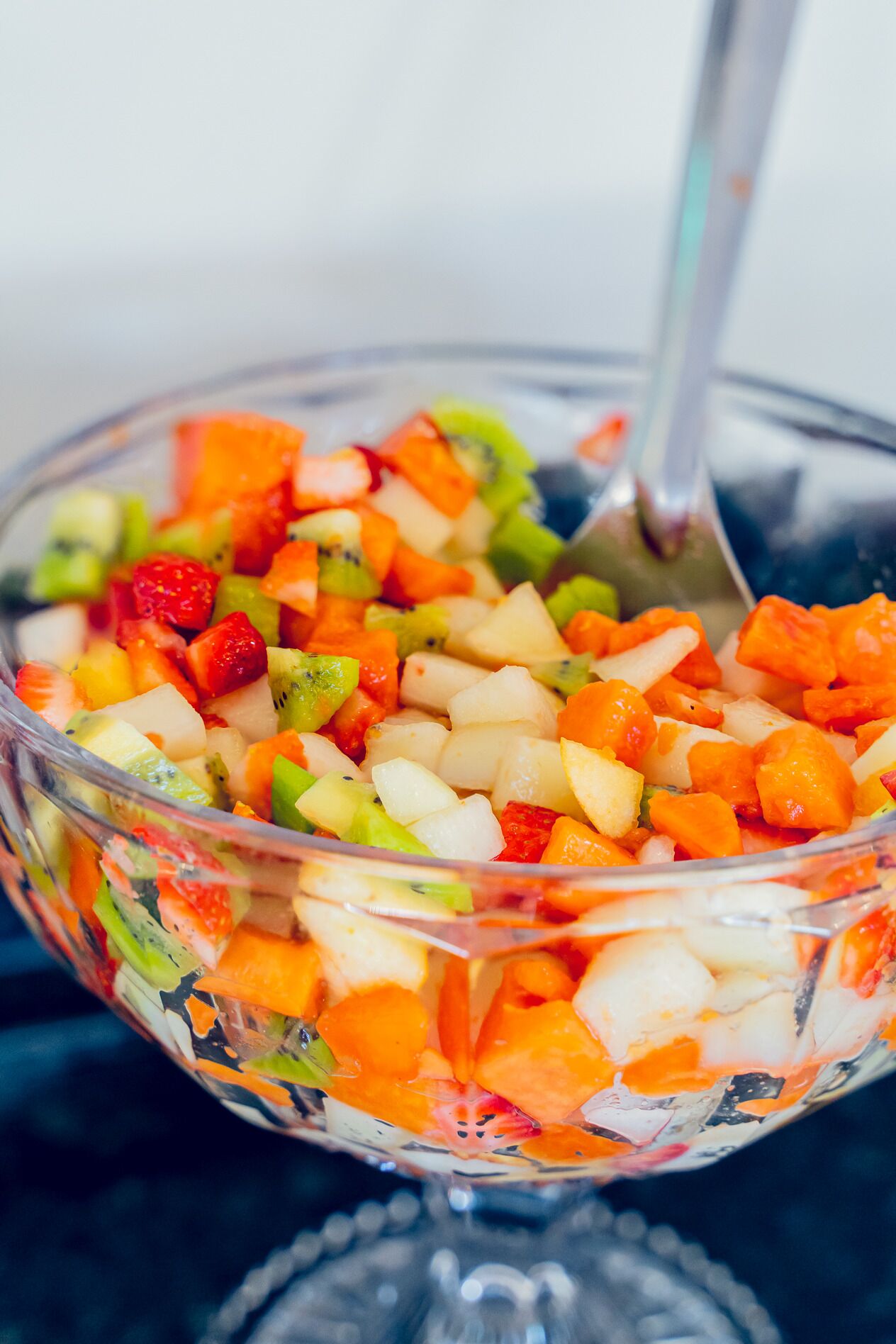 A clear glass bowl filled with a colorful fruit salad.
