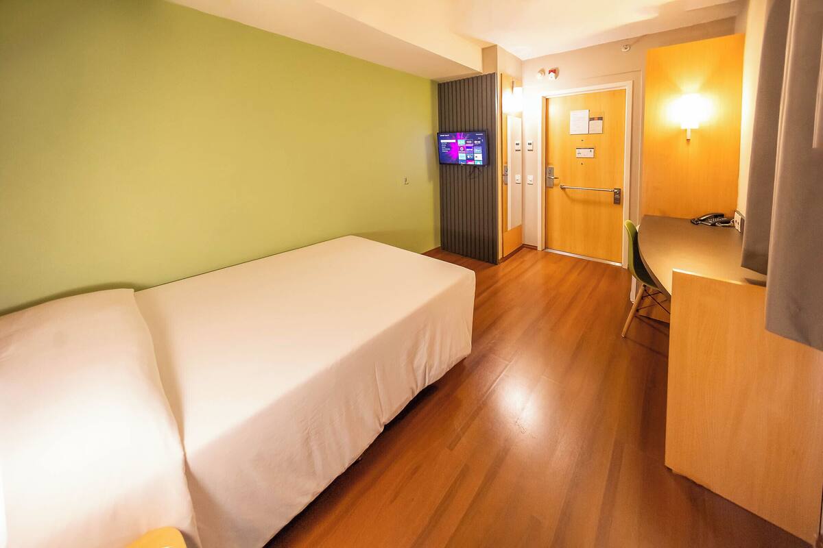 Une chambre d’hôtel avec un lit, un bureau et une télévision.