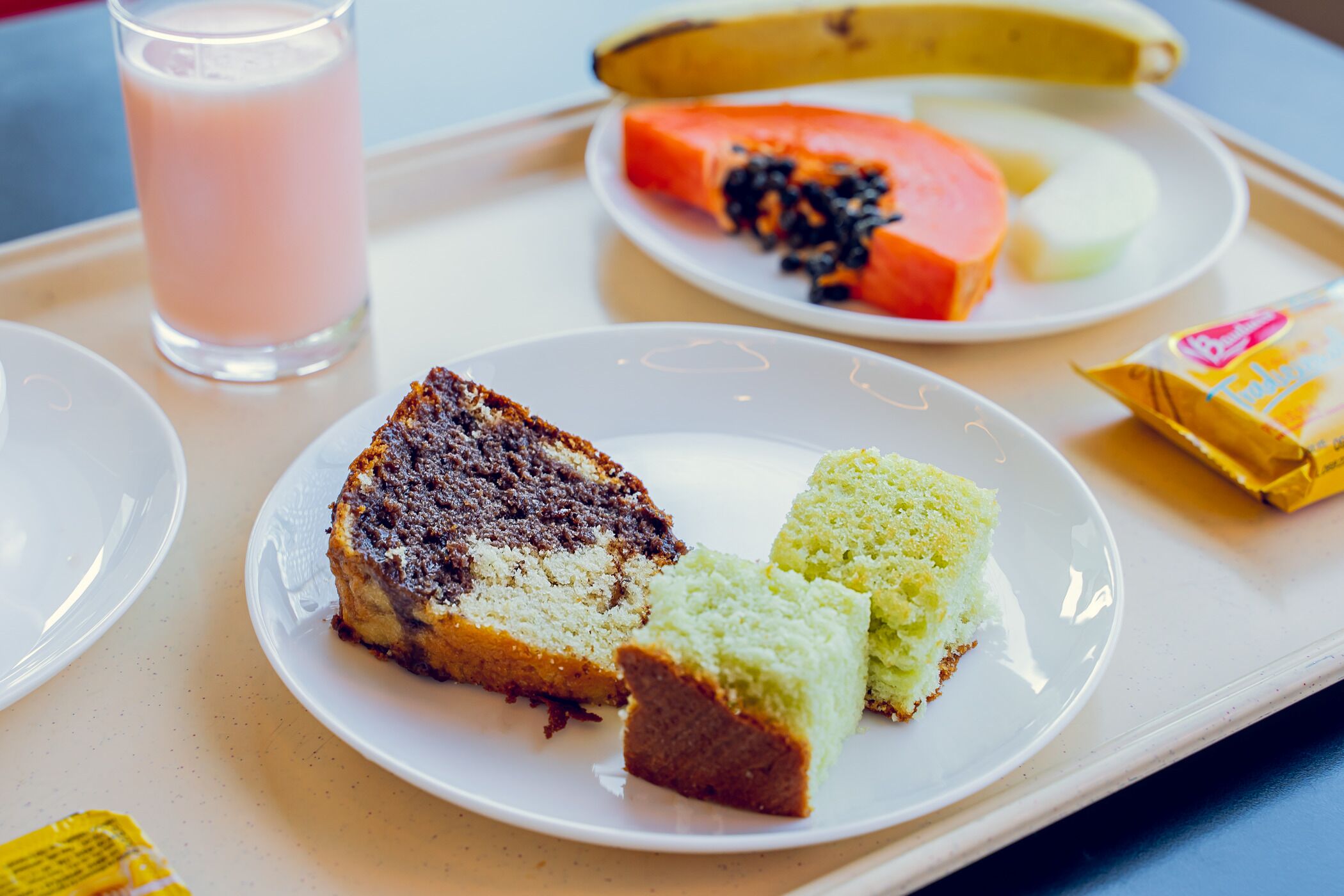 Una bandeja con una porción de pastel de chocolate, una porción de pastel de limón y una porción de pastel de coco sobre un plato blanco.