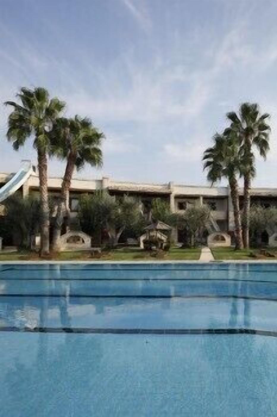 Una piscina con palmeras y un edificio al fondo.