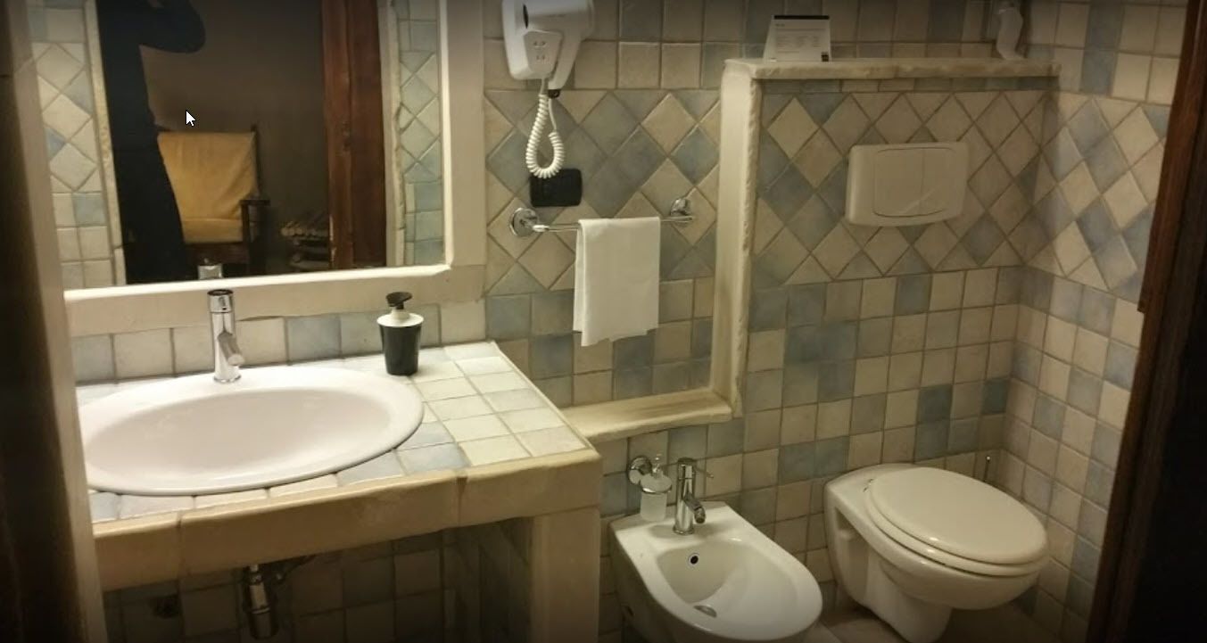 A bathroom with a sink, bidet, toilet, and a mirror.