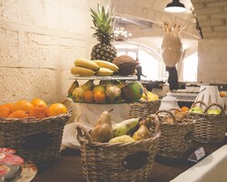 Una exhibición de frutas con plátanos, piña, naranjas, peras y manzanas en cestas.