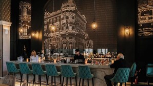 Un espace bar agrémenté d’une fresque représentant un bâtiment, de tabourets de bar et d’un barman.